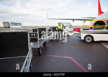 Arbeitnehmer, das Gepäck im Anhänger auf Start- und Landebahn Stockfoto