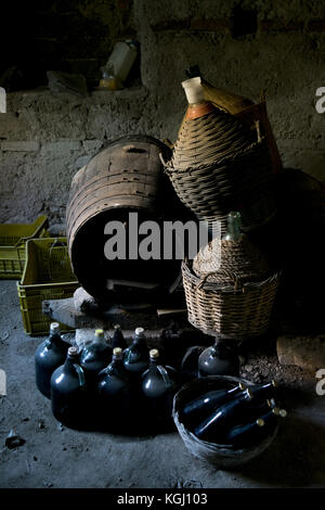 Unterirdischen Weinkeller mit reifer Wein Flaschen, Fässer und alte Stroh gedeckten Korbflaschen Stockfoto