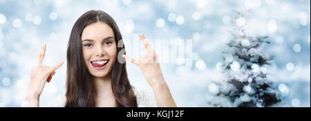 Happy Christmas Party Konzept Frau einen Rock und Roll Symbol auf unscharfen Golden Lights Stockfoto