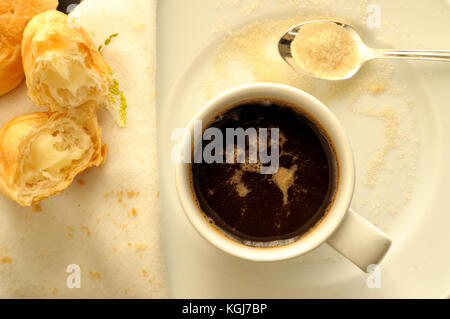 Blick von oben auf eine Tasse Espresso Italienisch, mit einem Teelöffel braunen Zucker und Croissants mit Creme gefüllt Stockfoto