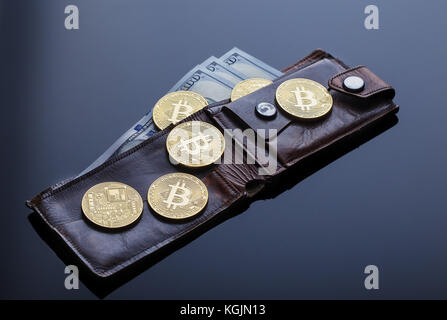 Wallet mit Gold bitcoins und einem Hundert-euro-Scheine auf einem dunklen Hintergrund. Das Konzept der virtuellen Wirtschaft und Währung. Stockfoto