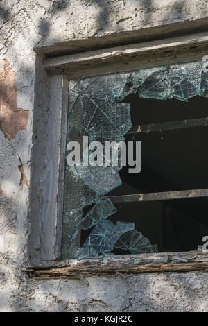 Zerbrochene / zertrümmerte Fenster aus verstärktem Glas. Metapher für Vandalismus, zerbrochene Träume, zerbrochenes Glas, zerbrochenes Glasfenster und allgemeines 'zerbrochenes' Konzept Stockfoto