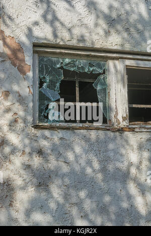 Zerbrochene / zertrümmerte Fenster aus verstärktem Glas. Metapher für Vandalismus, zerbrochene Träume, zerbrochenes Glas, zerbrochenes Glasfenster und allgemeines 'zerbrochenes' Konzept Stockfoto