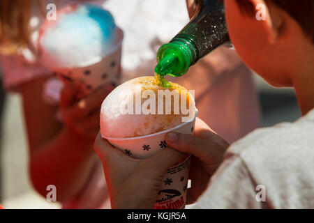 Suwanee, GA, USA - 6. Mai 2017: Eine Flasche gießt grün Sirup auf eine Schnee Kegel, ein Kind, ein Hund Woofstock Festival in Suwanee Stadt Ctr hält. Stockfoto