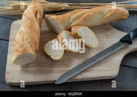 Baguette in Scheiben geschnitten auf Holz Schneidebrett mit verschiedenen Brot und Brötchen Stockfoto