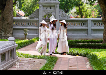 Junge vietnamesische Frauen, die die traditionelle Kleidung Ao Dai und der Konischen hat nicht La Lage; Garten der Tempel der Literatur in Hanoi, Vietnam Stockfoto