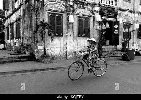 Früh morgens am Bach Dang Straße in der Altstadt von Hoi An, Vietnam. Eine Frau auf dem Weg von ihrem Einkauf am Morgen Markt. Stockfoto