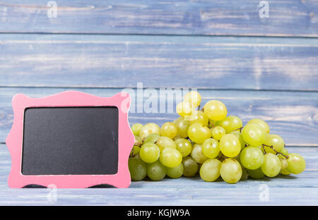 Gelbe Trauben mit gerahmten Blackboard auf hölzernen Hintergrund als Wein Werbung Konzept oder reiche Ernte fallen Stockfoto