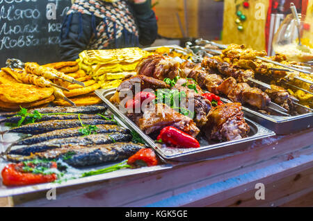 Heiß zubereitetes gegrilltes Fleisch und Fisch auf der Theke des Essensstandes auf der Weihnachtsmesse in Kiew, Ukraine Stockfoto