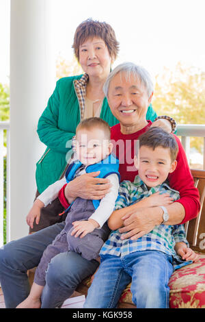 Senior nach chinesischen Paar mit ihren gemischten Rennen Enkelkinder Stockfoto