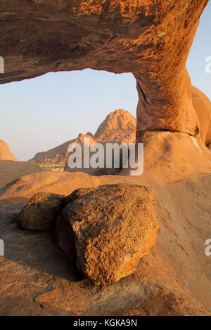 Grosse Granitfelsen arch bei Sonnenaufgang mit der spitzkoppe Mountain auf dem Hintergrund in Namibia Stockfoto