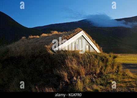 Holzhaus mit traditionellen Grasnabe Dach in hügeliger Landschaft, reykjadiskur, Insel Stockfoto