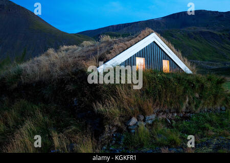 Holzhaus mit traditionellen Grasnabe Dach in hügeliger Landschaft, reykjadiskur, Insel Stockfoto