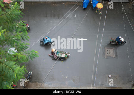 Luftaufnahme von einen Menschen auf den Roller und ein Verkäufer mit typischen vietnamesischen konischen Hüten und seine Barrow Spaziergänge durch die Straßen von Hanoi in Vietnam duri Stockfoto