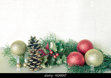 Goldene und rote Christbaumkugeln, Tannenzapfen und Holly Stockfoto