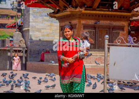 Kathmandu, Nepal Oktober 15, 2017: Unbekannter nepalesische Frau tragen typische Kleidung und mit einem Baby auf dem Arm, posiert für die Kamera, in einem Durbar Square in einem beautidul sonnigen Tag in der Nähe von Alte hinduistische Tempel in Kathmandu, Nepal Stockfoto