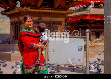 Kathmandu, Nepal Oktober 15, 2017: Unbekannter nepalesische Frau tragen typische Kleidung und mit einem Baby auf dem Arm, posiert für die Kamera, in einem Durbar Square in einem beautidul sonnigen Tag in der Nähe von Alte hinduistische Tempel in Kathmandu, Nepal Stockfoto