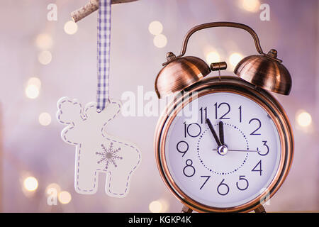 Vintage Kupfer Wecker mit fünf Minuten bis Mitternacht. Silvester Countdown. Holz Weihnachtsbaum reh Ornament hängend an Zweig. glitzernden garla Stockfoto