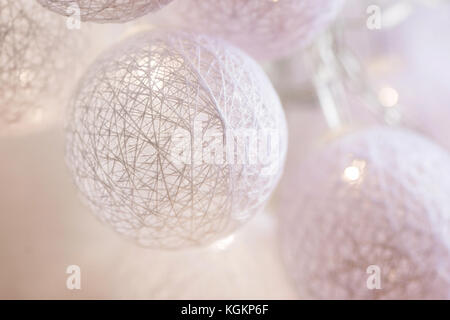 Weiße Baumwolle Kugeln Girlande hängen auf der Plank Holz Wand. skandinavischen Stil. glitzernden Lichter. Weihnachten Dekoration. neues Jahr. Gemütliche festliche Atmosphäre. Stockfoto