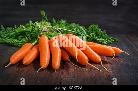 Bündel frische Karotten Gemüse mit grünen Blättern auf rustikalen hölzernen Hintergrund Stockfoto