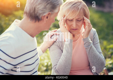 Traurige ältere Frau leidet unter Kopfschmerzen Stockfoto