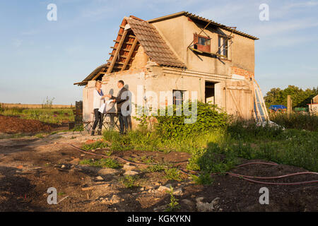 Immobilienmakler Händeschütteln mit Käufer während gegen Wohnhaus stehende Stockfoto