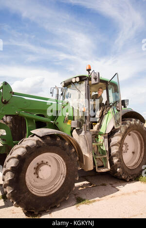Low Angle View der reifen Frau Fahren des Traktors gegen Sky Stockfoto