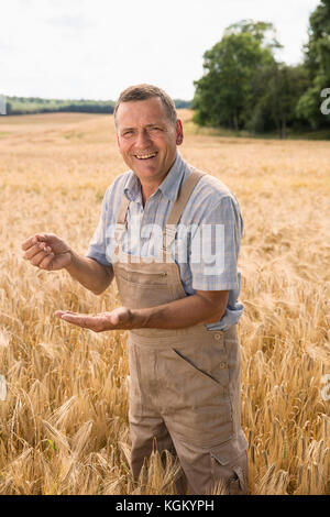 Portrait von Happy Bauer Holding Weizen beim Stehen im Feld in der Farm Stockfoto