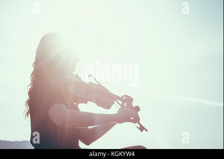 Low Angle View der Frau spielen Geige gegen Himmel an einem sonnigen Tag Stockfoto