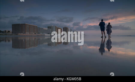 Junger Mann und eine Frau, die am Ufer am Strand gegen Himmel bei Sonnenuntergang, Daytona, Florida, USA Stockfoto