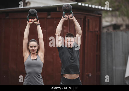 Männliche und weibliche Athleten Training mit Kettlebells während crossfit Ausbildung Stockfoto