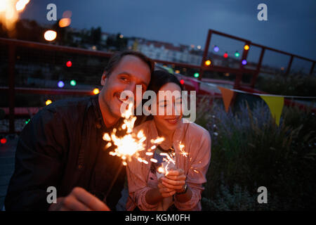 Glückliches Paar holding Wunderkerzen auf der Terrasse bei Nacht Stockfoto