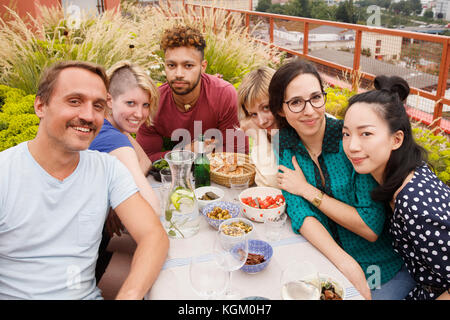 Portrait von glücklichen männlichen und weiblichen Freunden am Tisch im Freien mit Terrasse sitzen Stockfoto