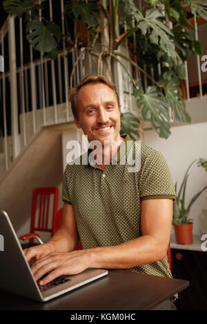 Portrait von glücklichen Mitte der Erwachsenen mit Laptop am Tisch Mann Stockfoto