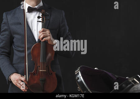 Mittelteil der Mann mit Violine, während von Fall zu Fall auf schwarzem Hintergrund stehend Stockfoto