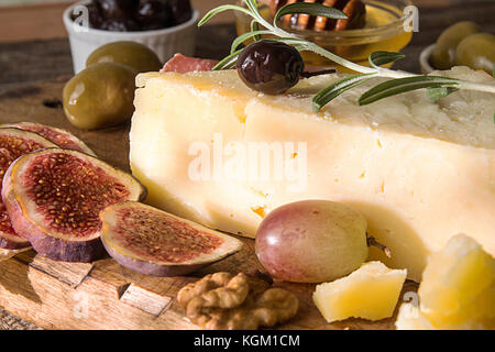 Stücksatz verschimmelten Käse, Schinken, eingelegten Pflaumen, Oliven, Feigen, Honig, Nüssen auf alten Holz- Hintergrund. Im rustikalen Stil. Stockfoto