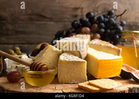 Die Zusammensetzung von Lebensmitteln mit Bausteinen von verschimmelten Käse, eingelegte Rosinen, Honig, Wein, Oliven, Feigen, Birnen, Cracker auf alten Holz- Hintergrund. Stockfoto