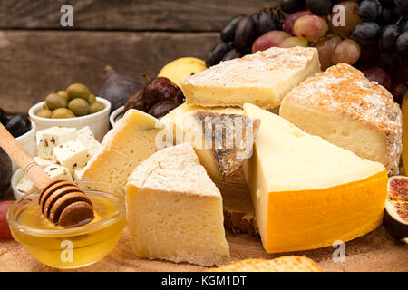 Die Zusammensetzung von Lebensmitteln mit Bausteinen von verschimmelten Käse, eingelegte Rosinen, Honig, Wein, Oliven, Feigen, Birnen, Cracker auf alten Holz- Hintergrund. Stockfoto