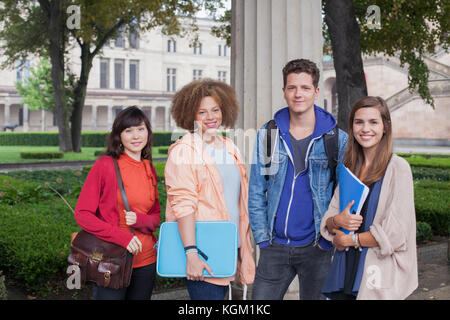 Porträt der jungen Freunde stehend gegen Spalte, Berlin, Deutschland Stockfoto