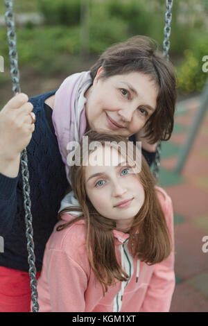 Portrait der älteren Frau mit Enkelin auf Schaukel am Spielplatz Stockfoto