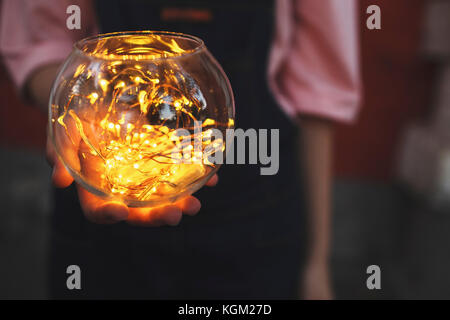 Zugeschnittenes Bild von Teenage girl Holding beleuchtete string Lichter in Glasschale Stockfoto