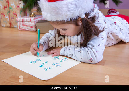 Kleine Mädchen die Vorbereitung der Santa schreiben. Sie malen die Geschenke, die Sie möchten. Pre-reader Konzept Stockfoto