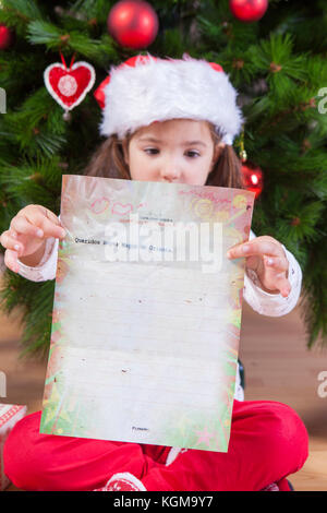 Kleines Mädchen, das den Brief der drei Weisen zeigt. Sie malte ein Blatt mit Kopfzeile auf Spanisch Stockfoto