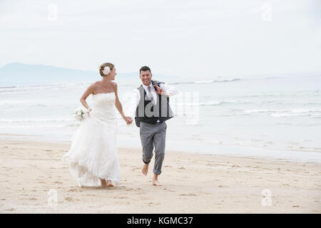 Fröhlich frisch verheiratete Ehepaar auf einem Sandstrand Stockfoto
