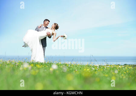 Bräutigam, die Braut in die Arme vor dem Meer Stockfoto