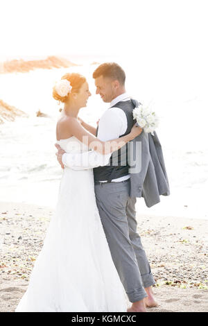 Glückliche Braut und Bräutigam am Strand bei Sonnenuntergang Stockfoto