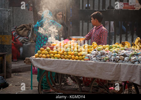 Delhi, Indien - 20. November 2015: Ein indischer Junge, der seine frischen Produkte auf einem überfüllten Straßenmarkt in Old Deli verkauft Stockfoto