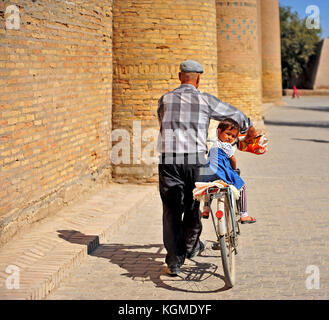 Chiwa, Usbekistan: kleines Mädchen sitzt auf einem Fahrrad von Ihrem Großvater. 14. September 2017. Stockfoto