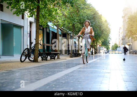 Ältere Frau reiten City Bike in der Stadt Stockfoto