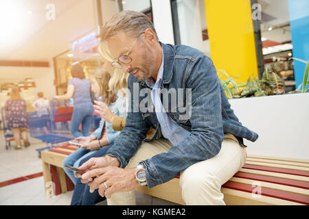 Mann sitzt auf öffentlichen Bank in der Shopping Mall Stockfoto